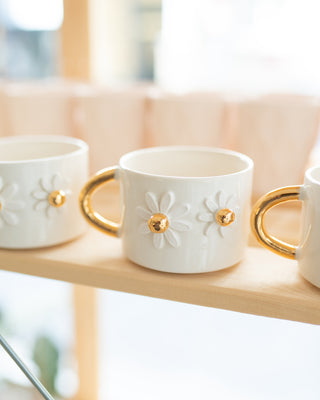 Handmade ceramic mug with 3D daisy motifs and a gold-plated handle, designed for coffee or tea. Elegant and charming, perfect for home or office use.